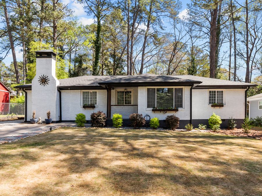 A renovated single-story home with white brick, black trim and a stone chimney